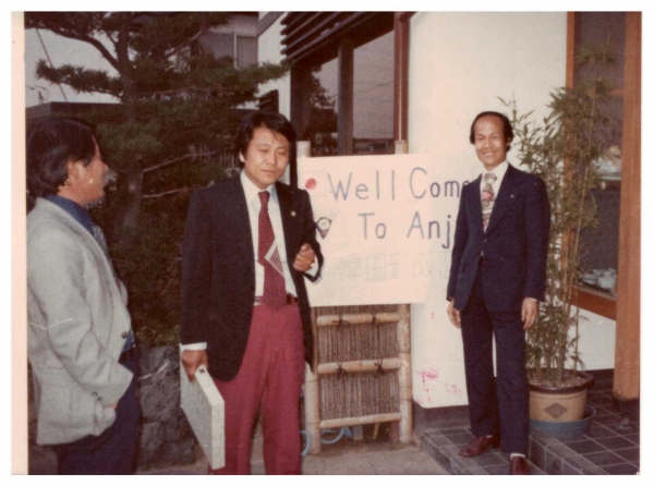 한국 안성JC 환영식장/ 일본 안성JC 회원들이 베푸는 환영회장 입구에서 찍은 일행 모습이다. 환영한다는 영어 문구가 건물 입구에 부착되어 있다(사진 오른쪽에 서있는 모습이 필자)
